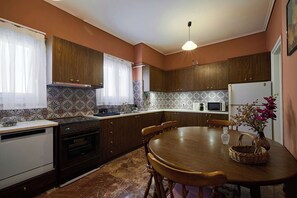 Una cocina con armarios de madera, estufa, microondas y una mesa de comedor con sillas.