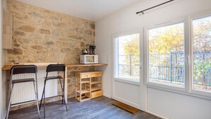A kitchen with a stone wall, a microwave, and a window with a view of a fence and trees.