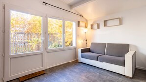 A room with a white sofa, a standing lamp, and a view through large windows.