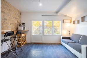 Une cuisine moderne avec un mur en pierre, un plan de travail blanc, un four à micro-ondes et un meuble en bois.