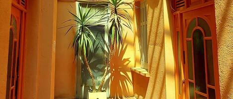 A narrow courtyard with tiled flooring, potted plants, and a sloped ceiling with skylights.