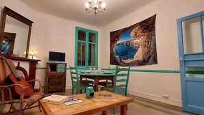 A room with a wooden table, a guitar, a chair, a TV, a painting, and a blue door. - 6-person apartment ideally located on the quiet side of the port (Port-Vendres)