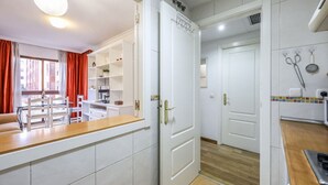 A modern kitchen with white cabinetry, a wooden countertop, and a view to the living area.