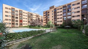 A modern apartment building with a swimming pool and a well-maintained garden.