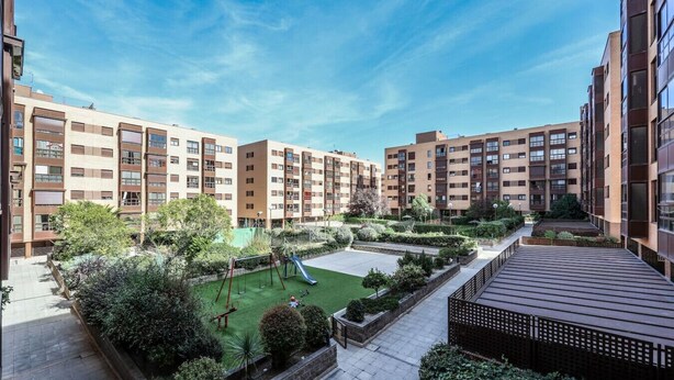 A residential building with multiple floors, a courtyard with greenery, and a playground.