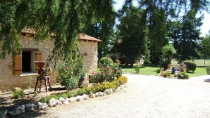 A stone building with a window and a door, surrounded by a garden with various plants and flowers. - Bed and Breakfast 'Chambre Double Carpediem Bergerac' with Shared Garden, Wi-Fi and Air Conditioning (Prigonrieux)