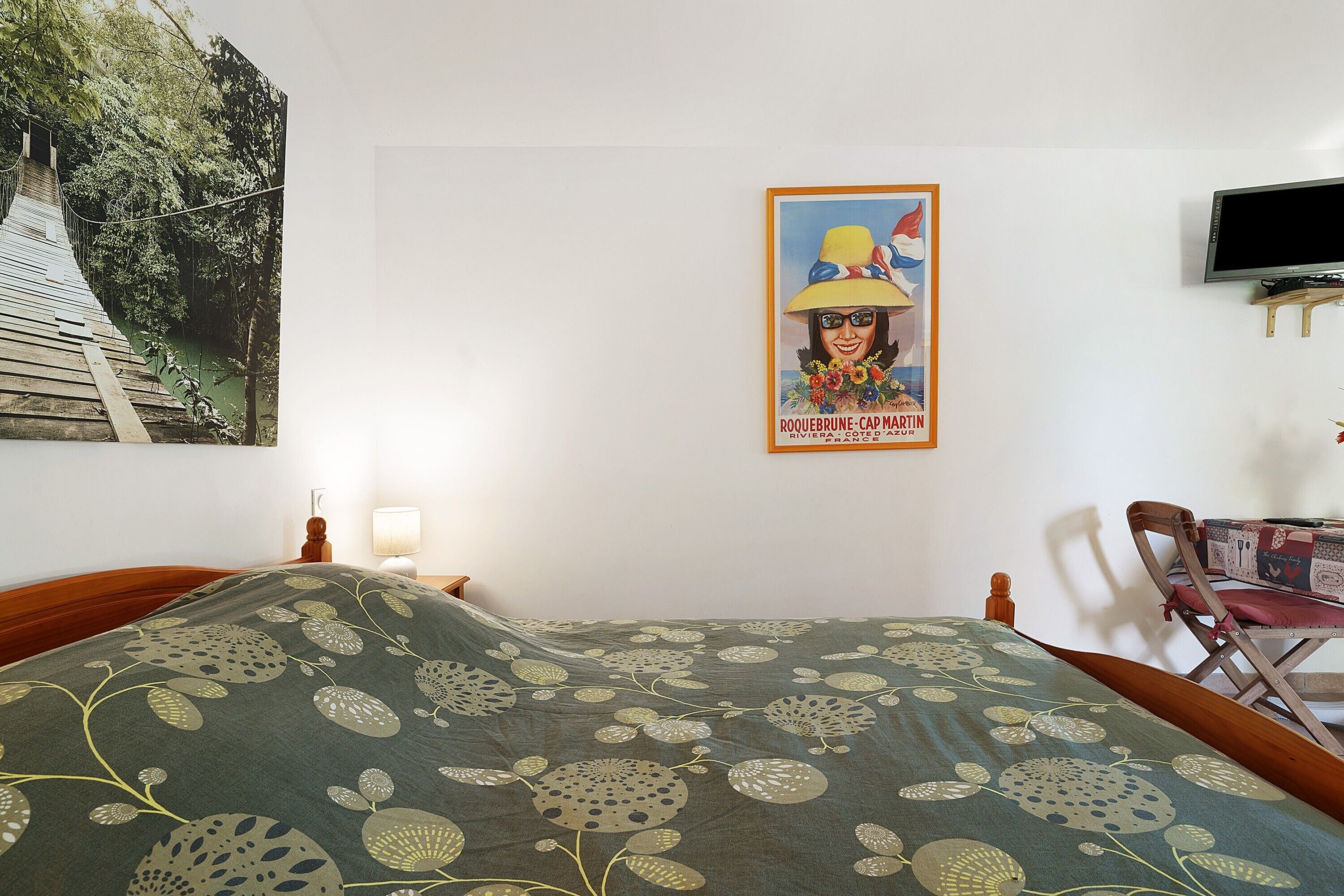 A bedroom with a bed, a poster on the wall, a television, and a chair.
