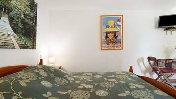 A bedroom with a bed, a poster on the wall, a television, and a chair.