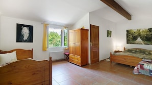 A bedroom with two wooden beds, a wardrobe, and a window with curtains.