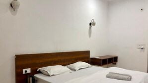 A double bed with white linens, a wooden headboard, bedside tables, and a wall-mounted light fixture. - Hotel AVG Palace (Tijara)
