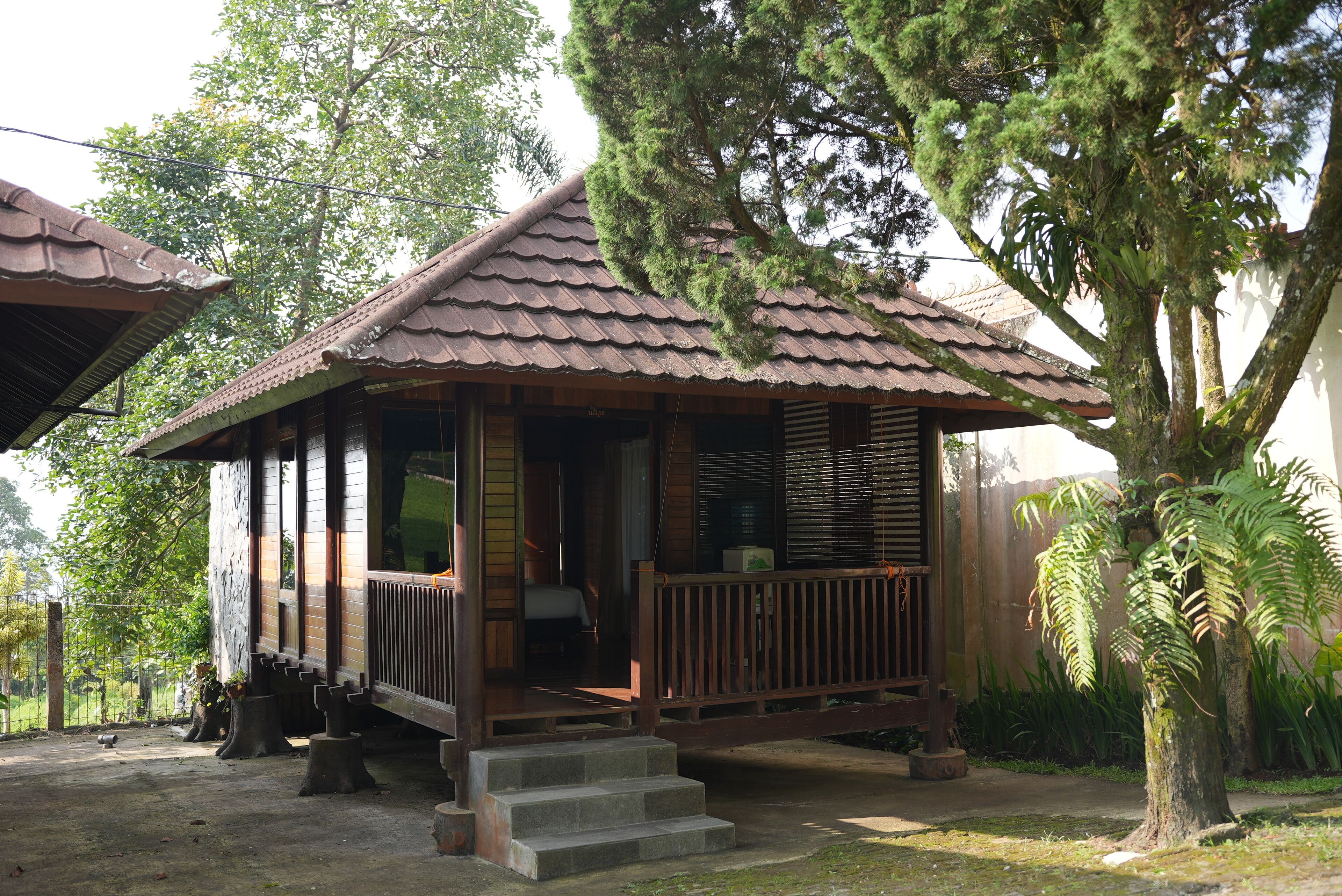 Ein traditionelles Holzhaus mit Ziegeldach, einer Veranda und Stufen zum Eingang.
