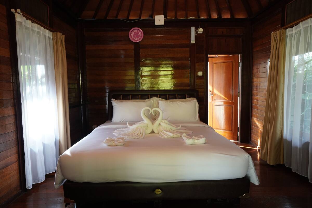 Une chambre rustique en bois avec un lit agrémenté d’une décoration en forme de cygne réalisée avec des serviettes.