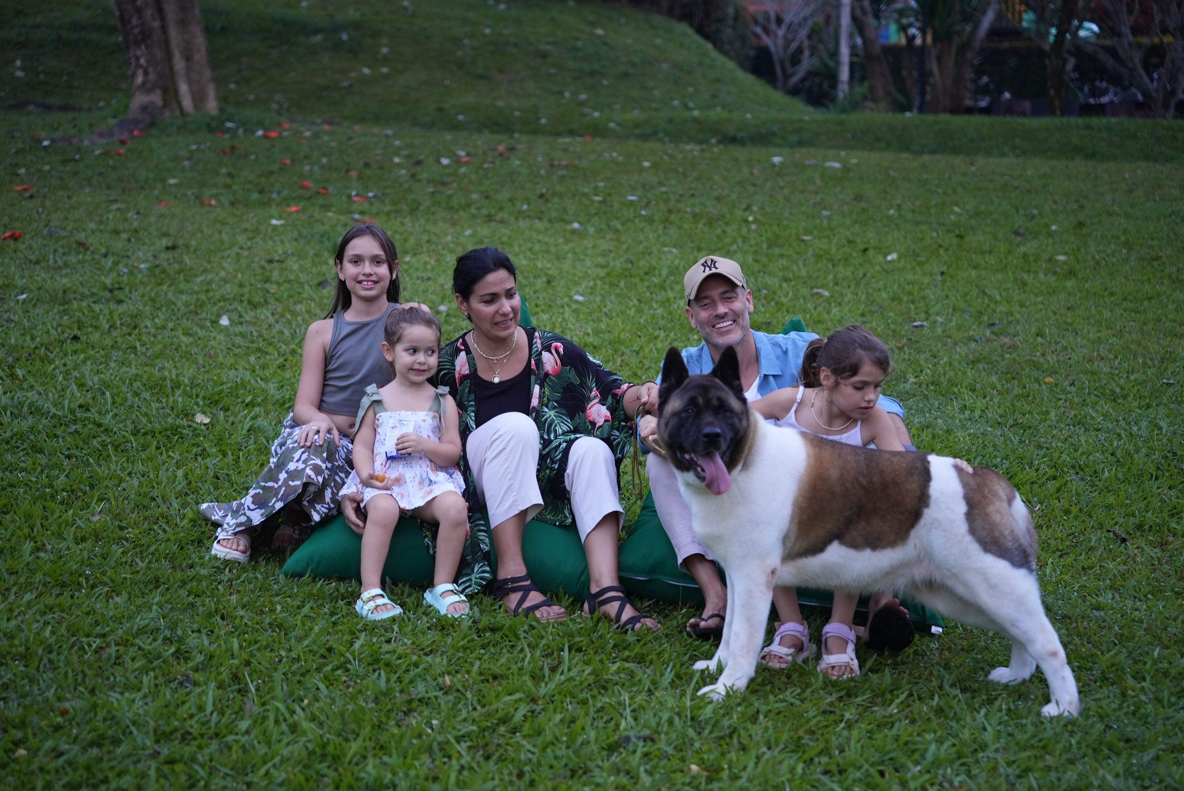 A group of people sitting on grass with a dog.