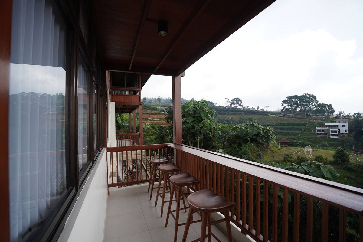 Un balcon avec des tabourets en bois et une vue sur un paysage rural.