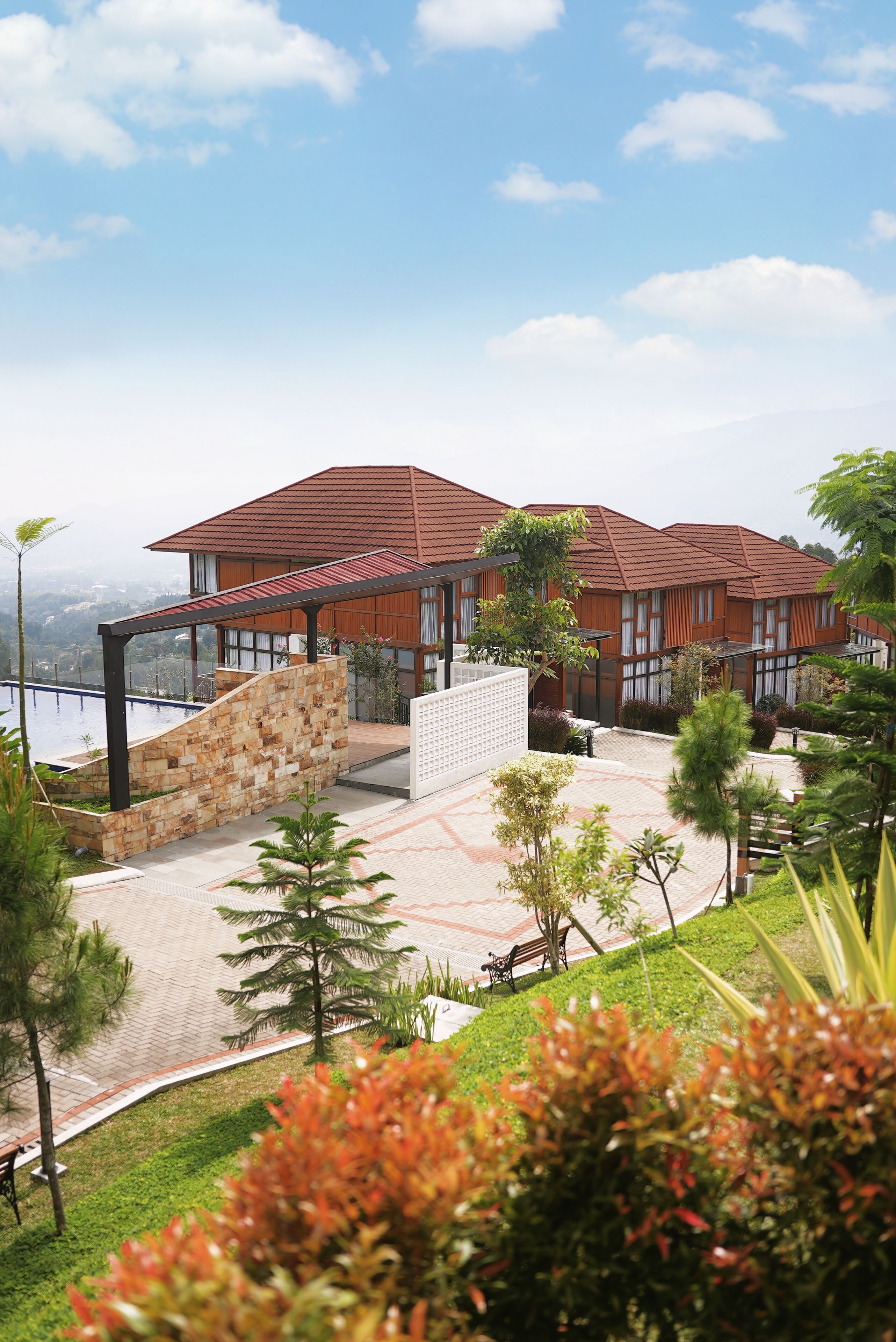 A modern building with a red roof, a swimming pool, and a landscaped garden.