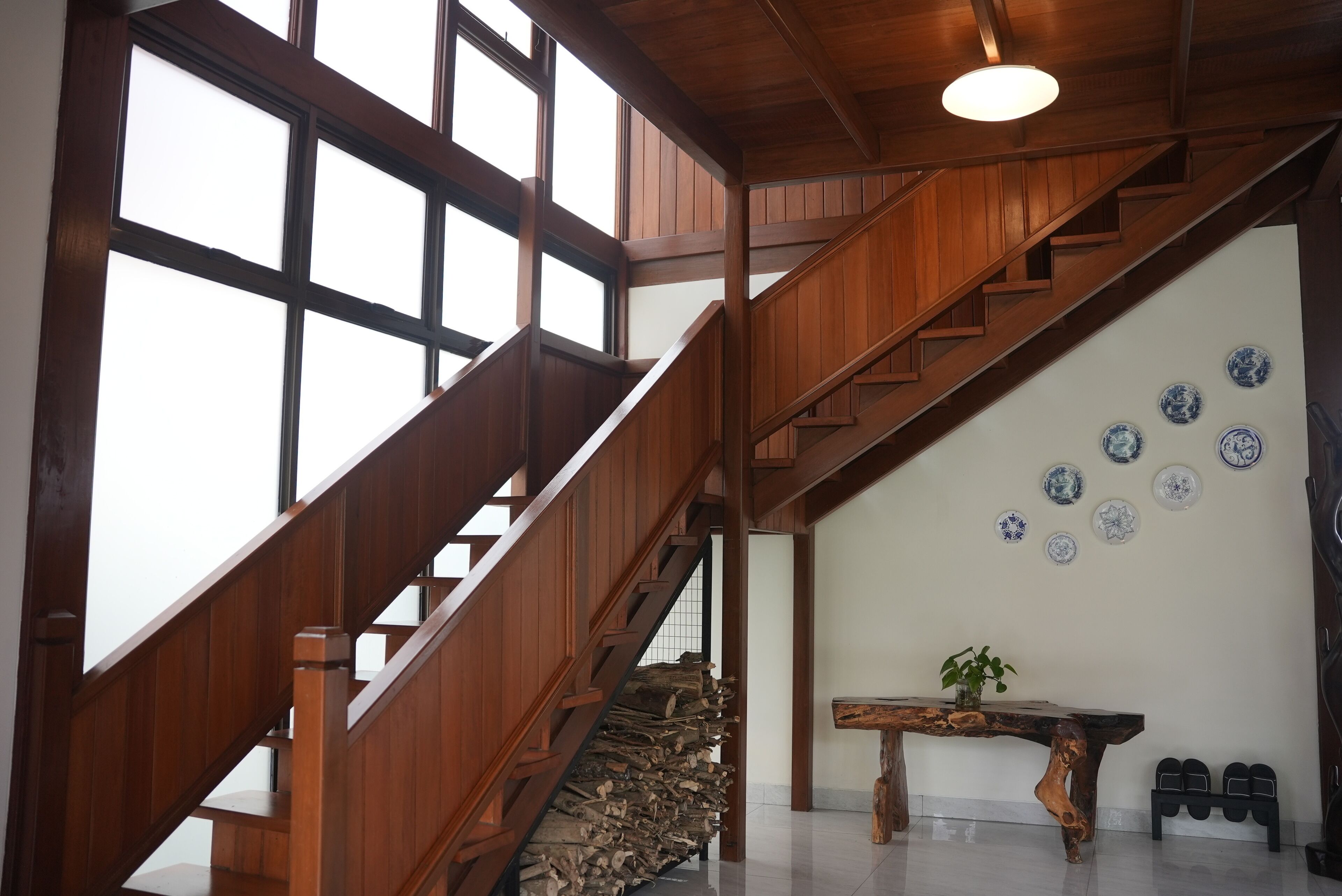 A wooden staircase with a view of the sky, a wall with decorative plates, and a table with a plant.