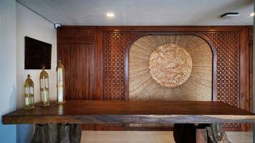 A wooden dining table with a unique woven backrest, three decorative candle holders, and a wall-mounted security camera.