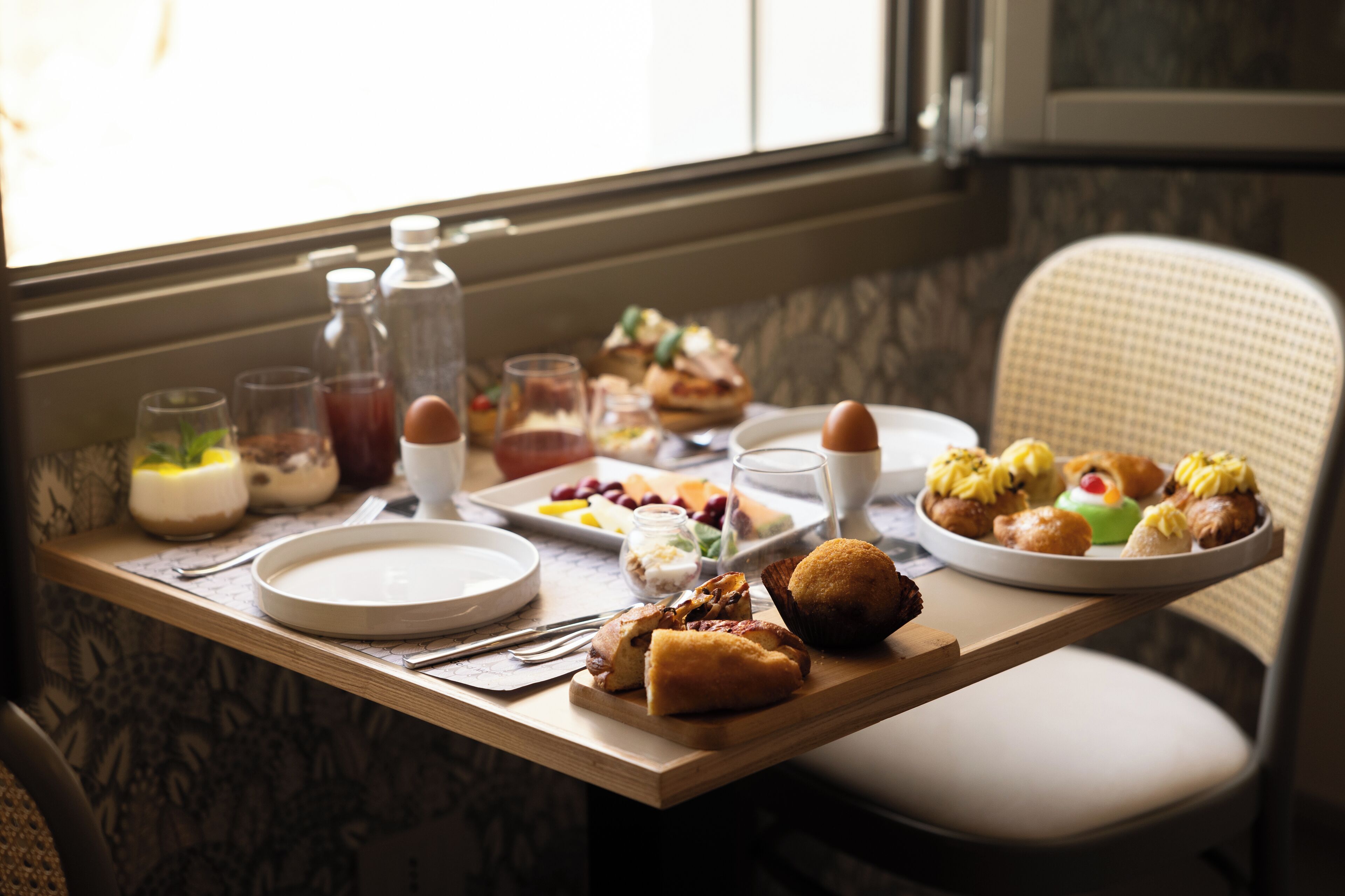 Una tavola imbandita per la colazione, con dolci, frutta e condimenti.