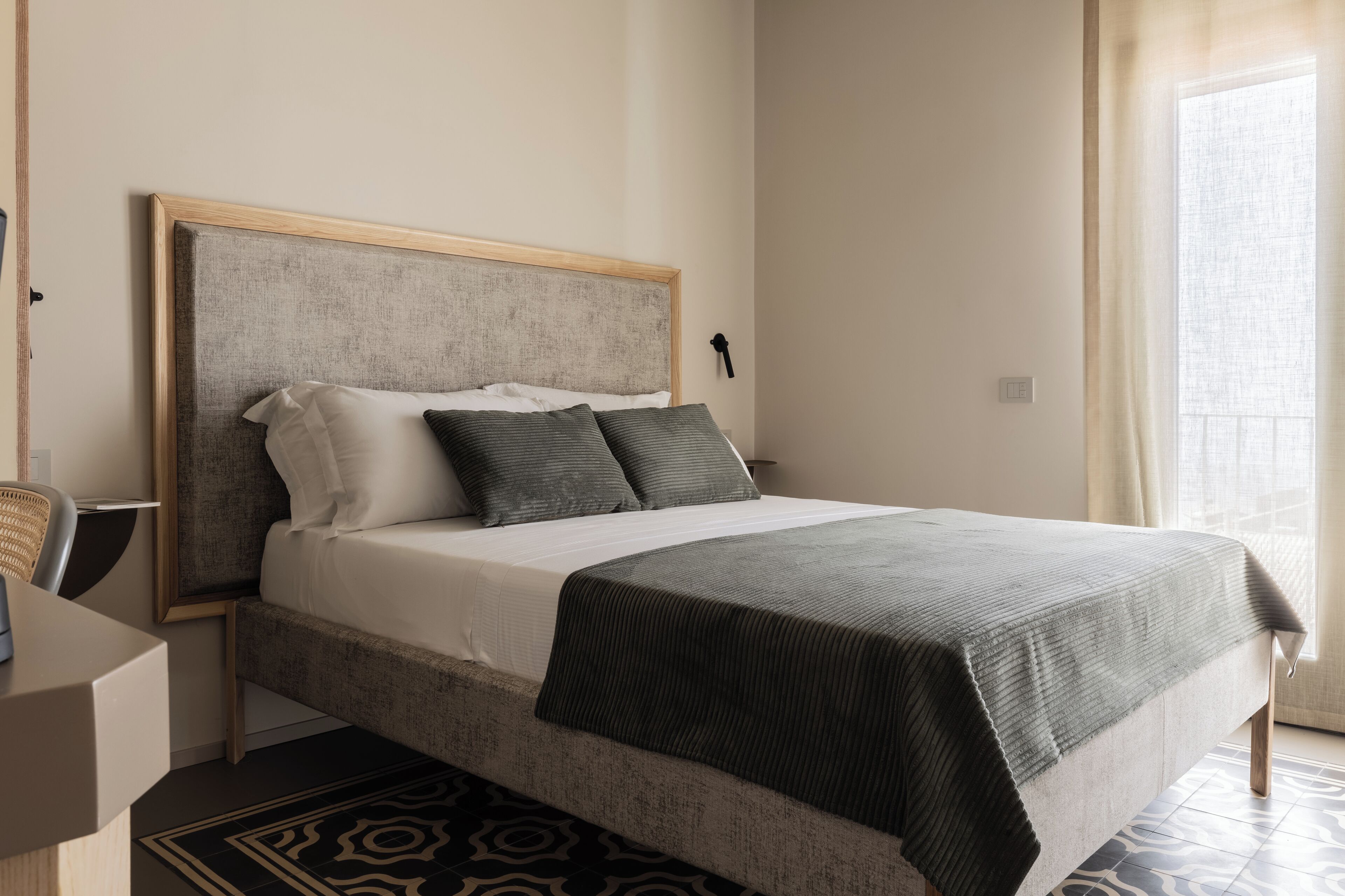 Un dormitorio ordenado con cama, mesita de noche y una silla.