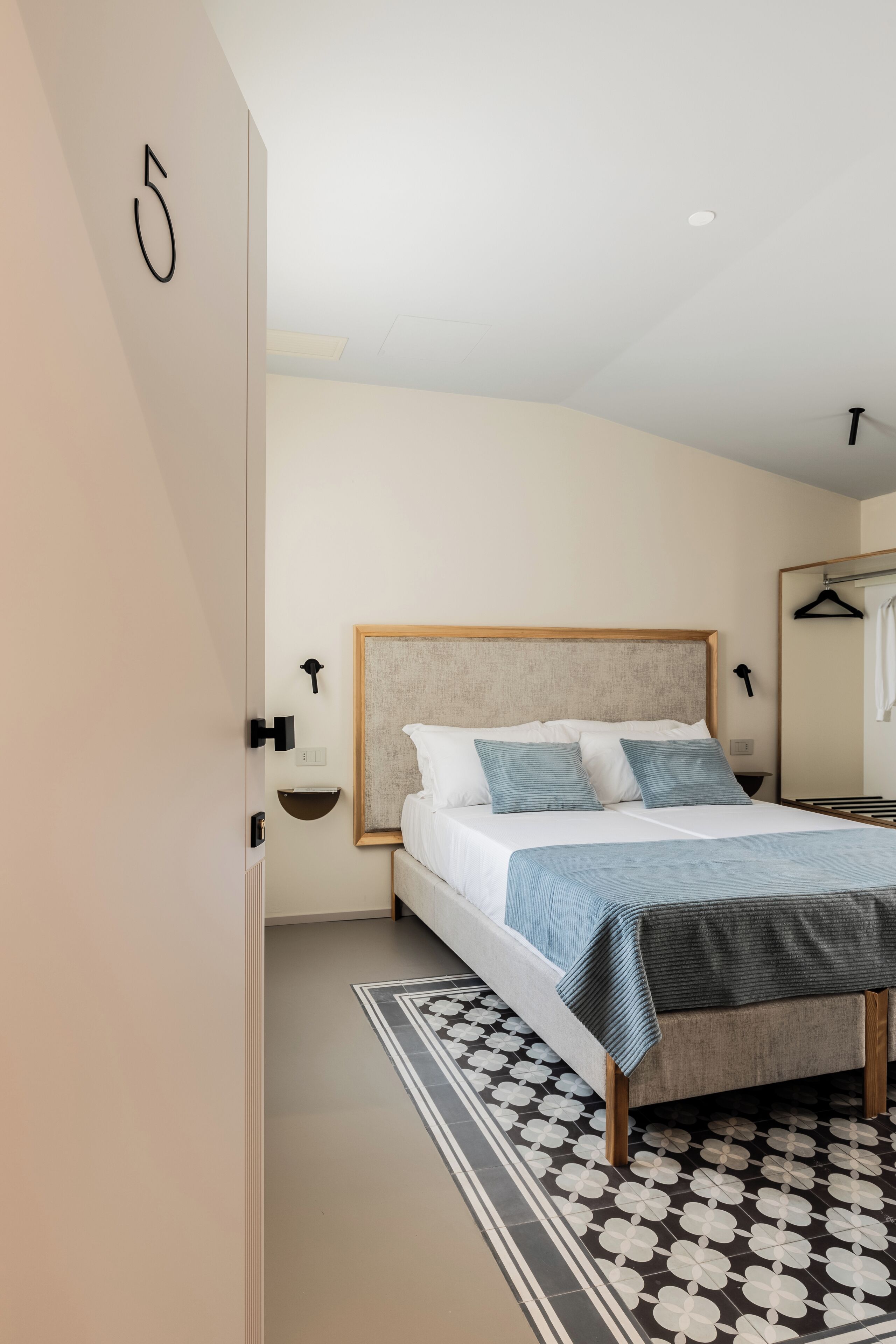 A modern bedroom with a bed, bedside tables, and a large mirror.