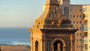 A historical building with a dome and arches, overlooking a coastal area with modern buildings in the background. - Domus Terravecchia  (Agrigento)