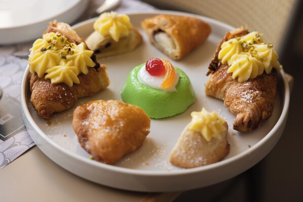 A plate of assorted pastries, including a green dessert with a cherry on top. - Domus Terravecchia (Agrigento)