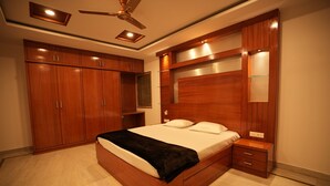 A bedroom with a large bed, wooden wardrobe, and built-in shelves. - Stylish 4-bedroom Family Getaway Luxury Living (Hyderabad)