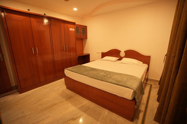 A bedroom with a large wooden wardrobe, a bed with a headboard, and a nightstand. - Stylish 4-bedroom Family Getaway Luxury Living (Hyderabad)