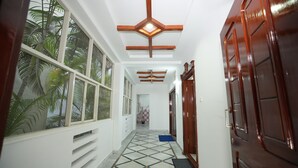 A hallway with a tiled floor, wooden ceiling beams, and a door on the right. - Stylish 4-bedroom Family Getaway Luxury Living (Hyderabad)