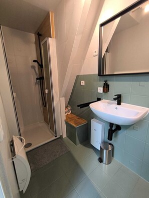 Een douche, handdoeken, zeep, toiletpapier