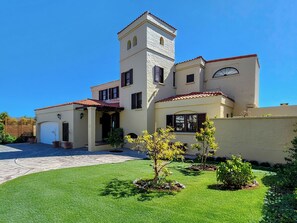 A two-story house with a tower, a covered porch, and a well-maintained lawn.