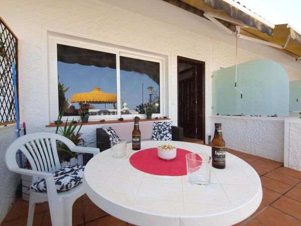 A round table with a red center, two white chairs, a bottle of beer, and a glass on the table.
