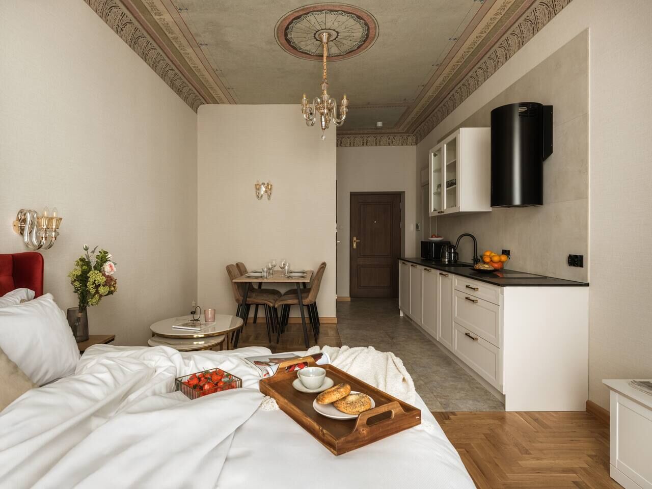 A bedroom with a bed, bedside table, and a breakfast tray with bread and fruit.