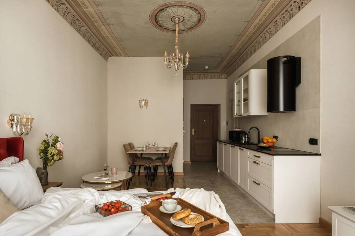 A bedroom with a bed, bedside table, and a breakfast tray with bread and fruit.