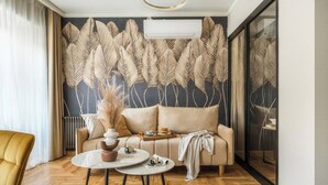A modern living room with a sofa, two round tables, and a decorative wall. - Art Palace by Fragola Collection (Kraków)