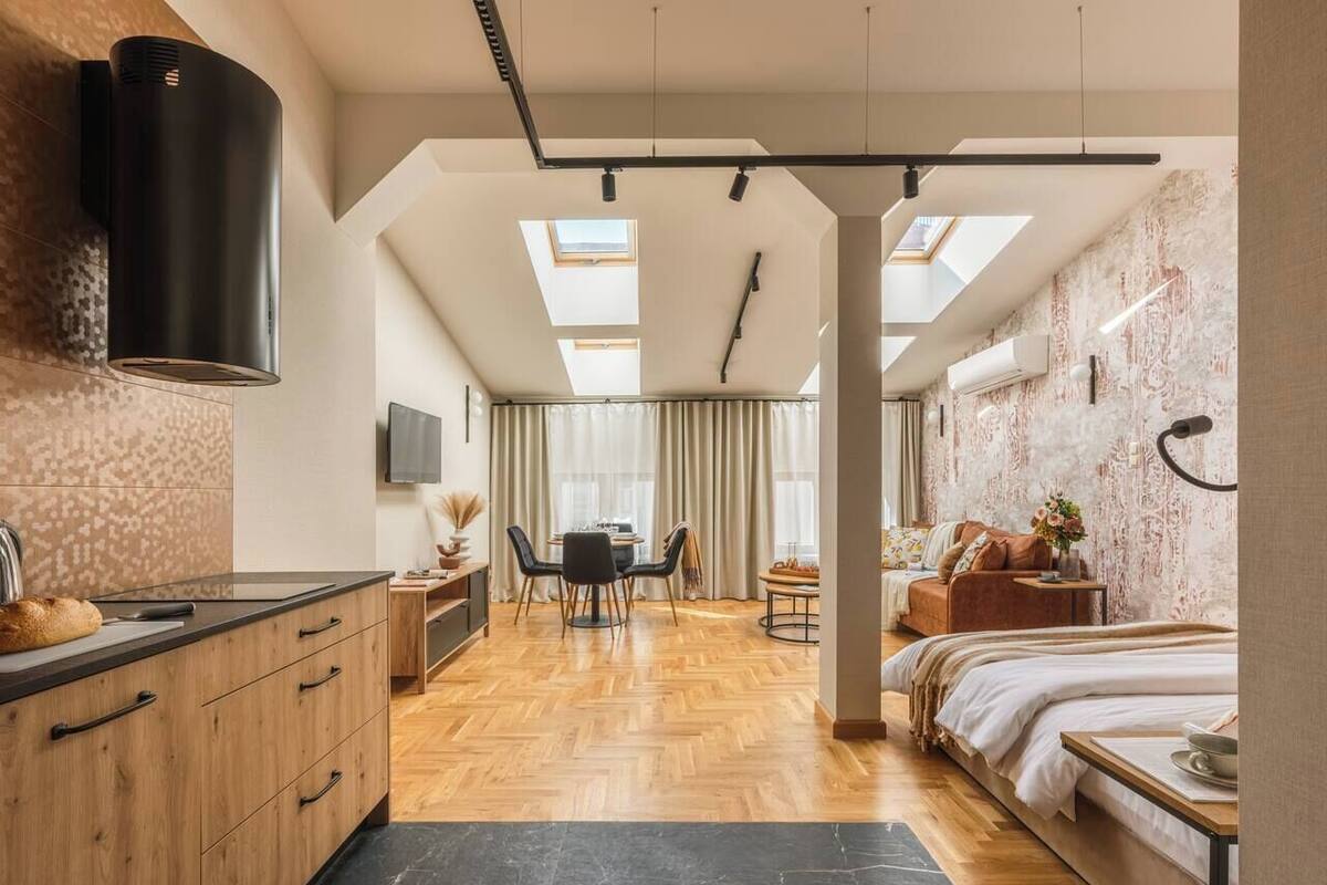 A modern hotel room with a kitchen, dining area, and a large bed.