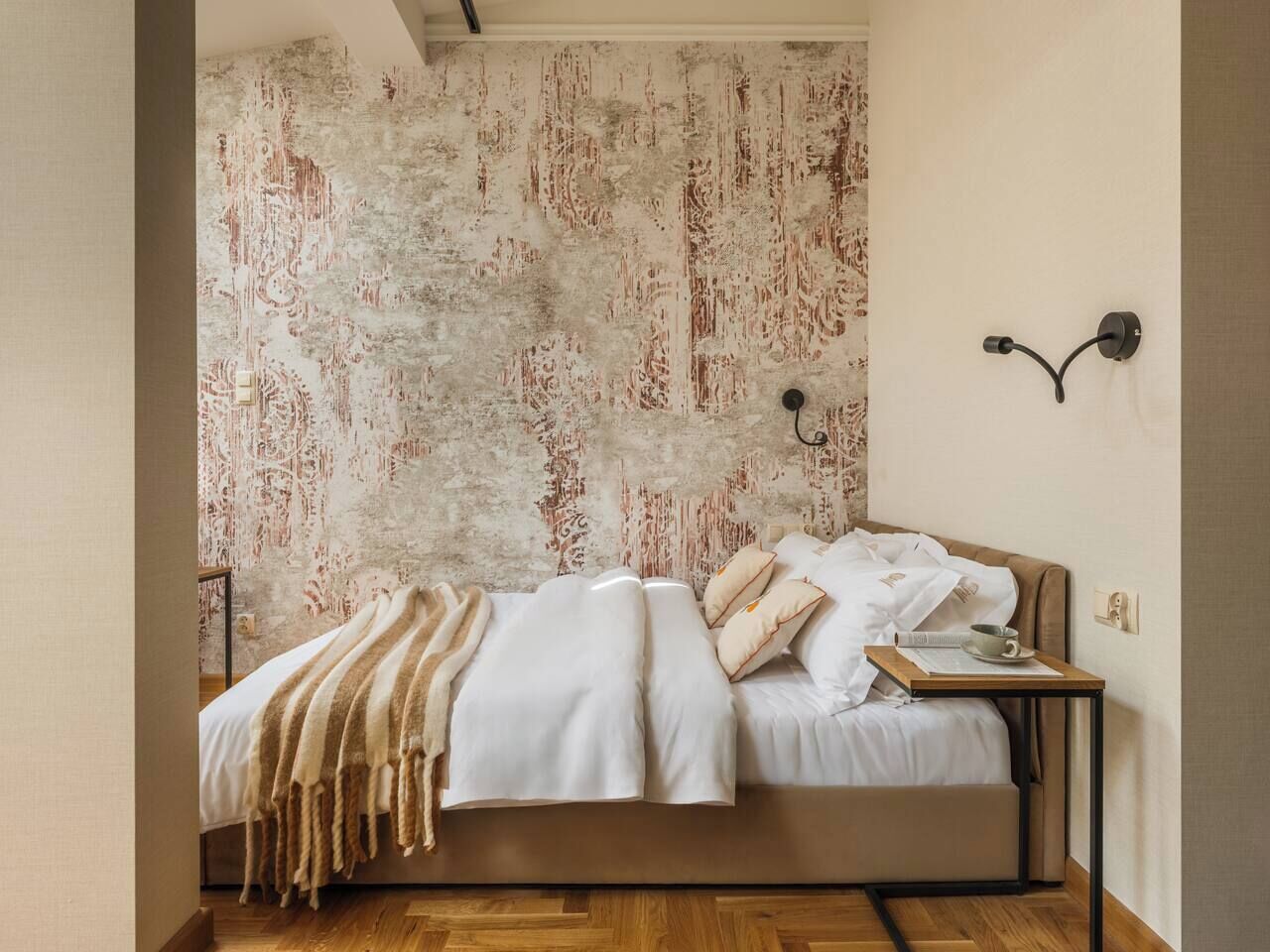 A bedroom with a bed, bedside table, and a textured wall.