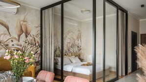 A modern room with a dining area, a bed with white bedding, and a large window with curtains. - Art Palace by Fragola Collection (Kraków)