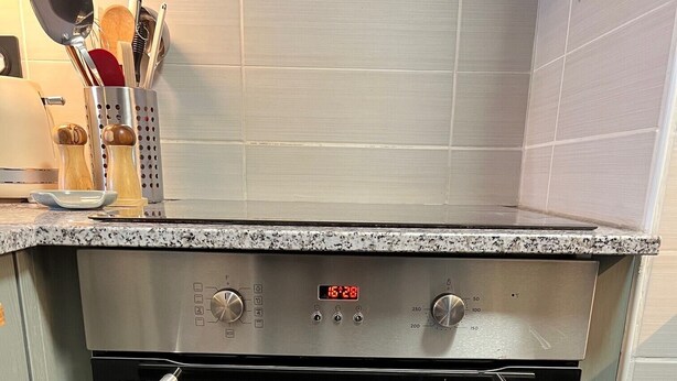 Une cuisine équipée d’un four encastré, de poignées en acier inoxydable et d’un plan de travail en granit.