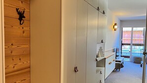Un couloir avec un lambris en bois sur un côté, une armoire blanche à plusieurs portes et un banc.
