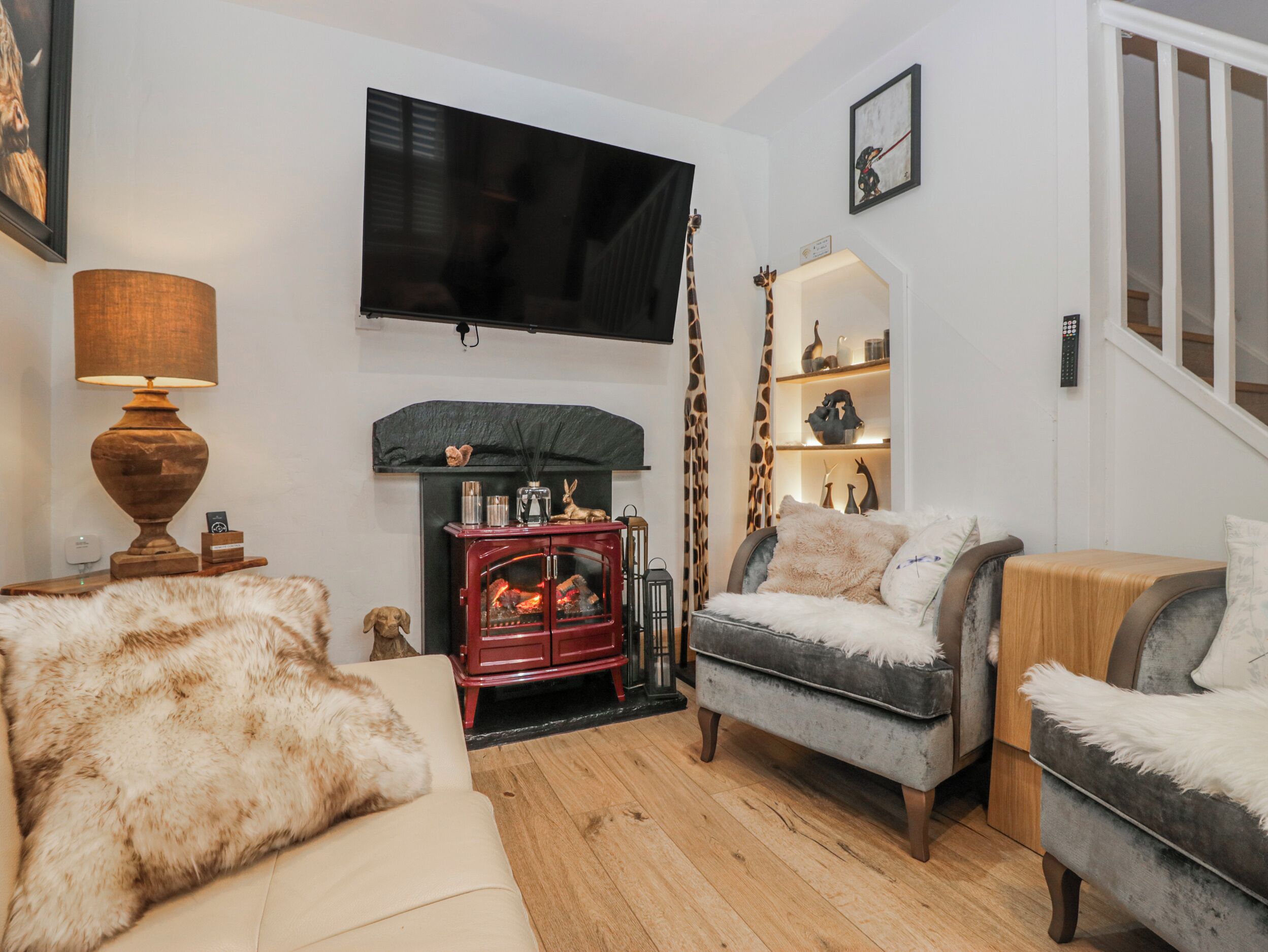 Ein gemütliches Wohnzimmer mit Kamin, einem an der Wand befestigten Fernseher und einer Treppe, die zu einer weiteren Ebene führt.