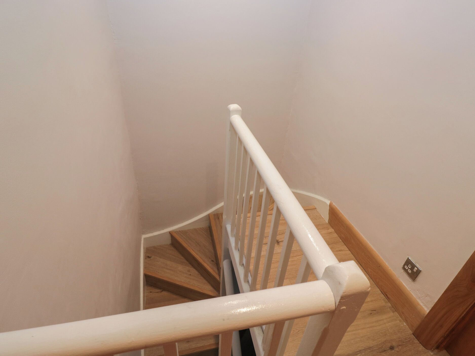 Eine Holztreppe mit weißen Geländern und einer hellen Wand.