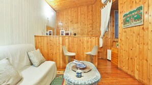 A cozy room with a wooden interior, a sofa, two chairs, a small table with a bowl and mug, and a picture on the wall. - GuestHost - Cozy 45 sqm apartment, perfect for 2 people, located on the ground floor of a historic building (1 step to access). A stone's throw from Spaccanapoli (in the restricted traffic zone), the property is ideal for those who want to fully experien (Naples)