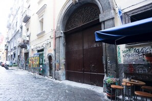 A narrow street with a closed shop with a large wooden door and a blue awning.