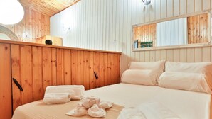 A wooden-paneled room with a bed, towels, a mirror, and a small shelf with a lamp. - GuestHost - Cozy 45 sqm apartment, perfect for 2 people, located on the ground floor of a historic building (1 step to access). A stone's throw from Spaccanapoli (in the restricted traffic zone), the property is ideal for those who want to fully experien (Naples)