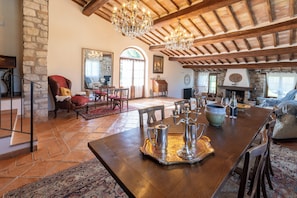 A spacious living area with a wooden dining table, stone walls, and a fireplace.