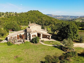A stone house with a sloped roof, surrounded by lush greenery and hills. - NEW - The Lost Stone country paradise with pool, AC & breathtaking country views (Todi - PG)