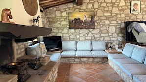 Una habitación con paredes y chimenea de piedra, un sofá y un televisor.