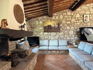 A stone-walled room with a stone fireplace, a sofa, and a television. - NEW - The Lost Stone country paradise with pool, AC & breathtaking country views (Todi - PG)