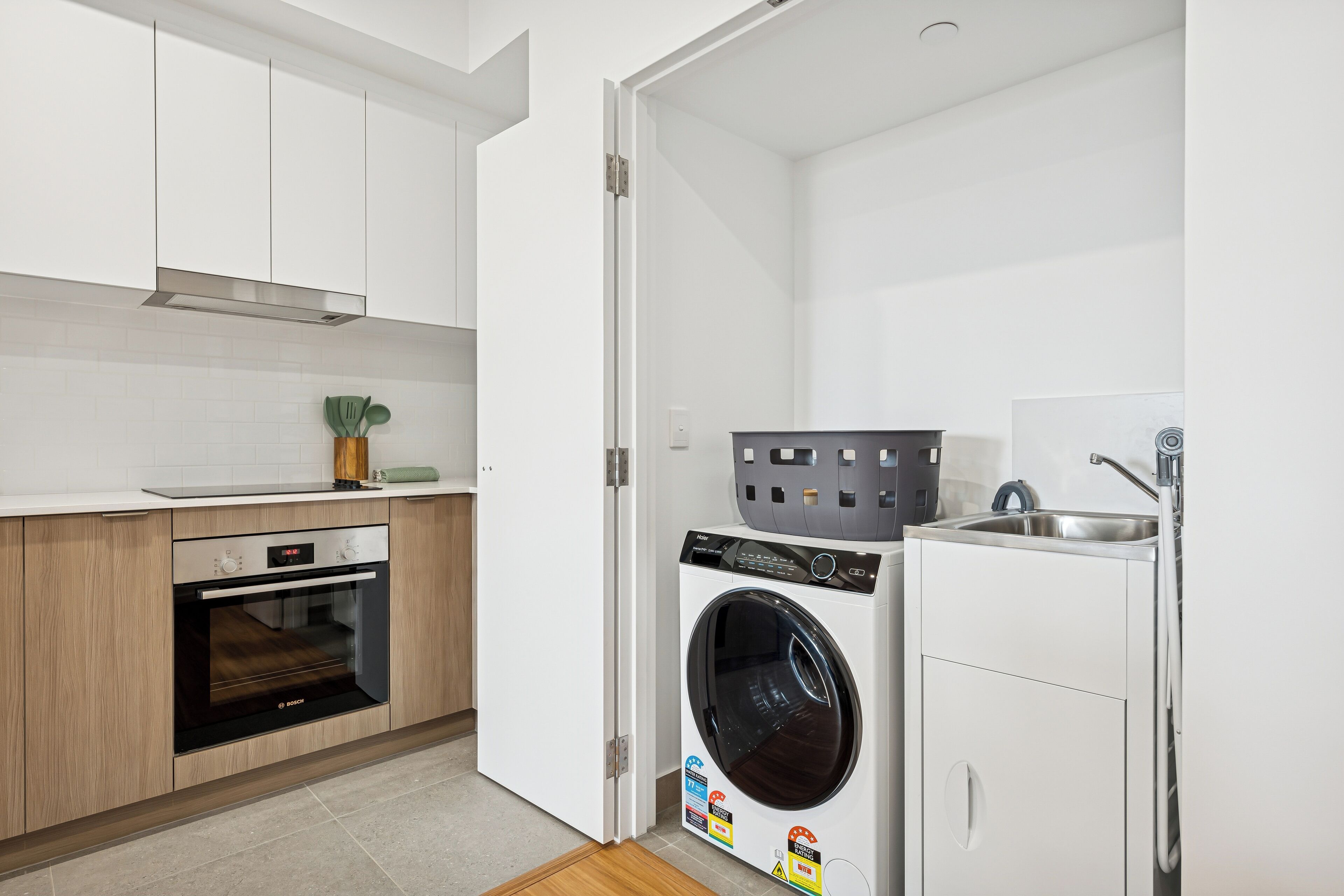 A compact kitchen with a Bosch oven, a front-loading washing machine, and a sink.